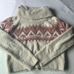 Lose turtleneck cream sweater with a pink and brown pattern.